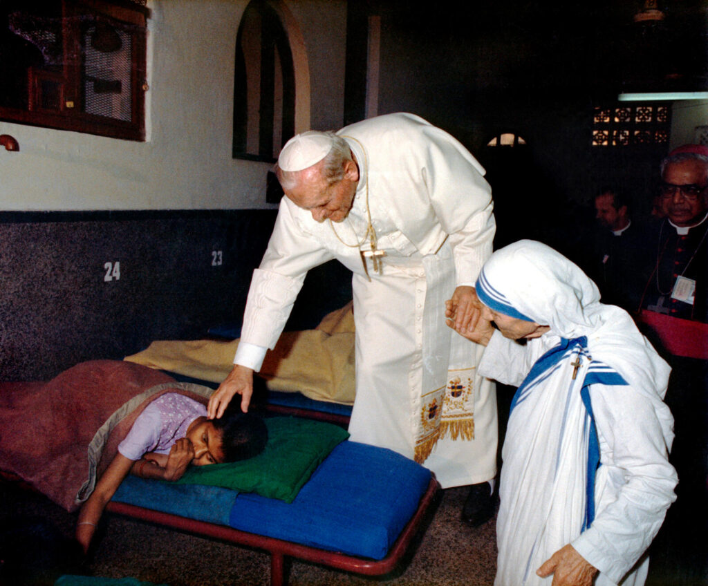 Mother Teresa with the Pope visiting a sick person.