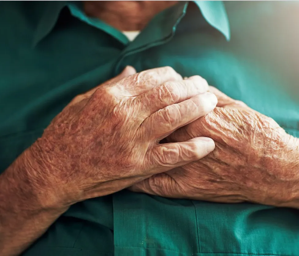 close up of hands of elderly man experiencing heart pain